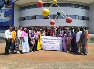 Attendees gather outside in front of a sign and smile for a group picture