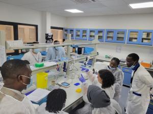 A group of workshop attendees wearing white coats in a lab